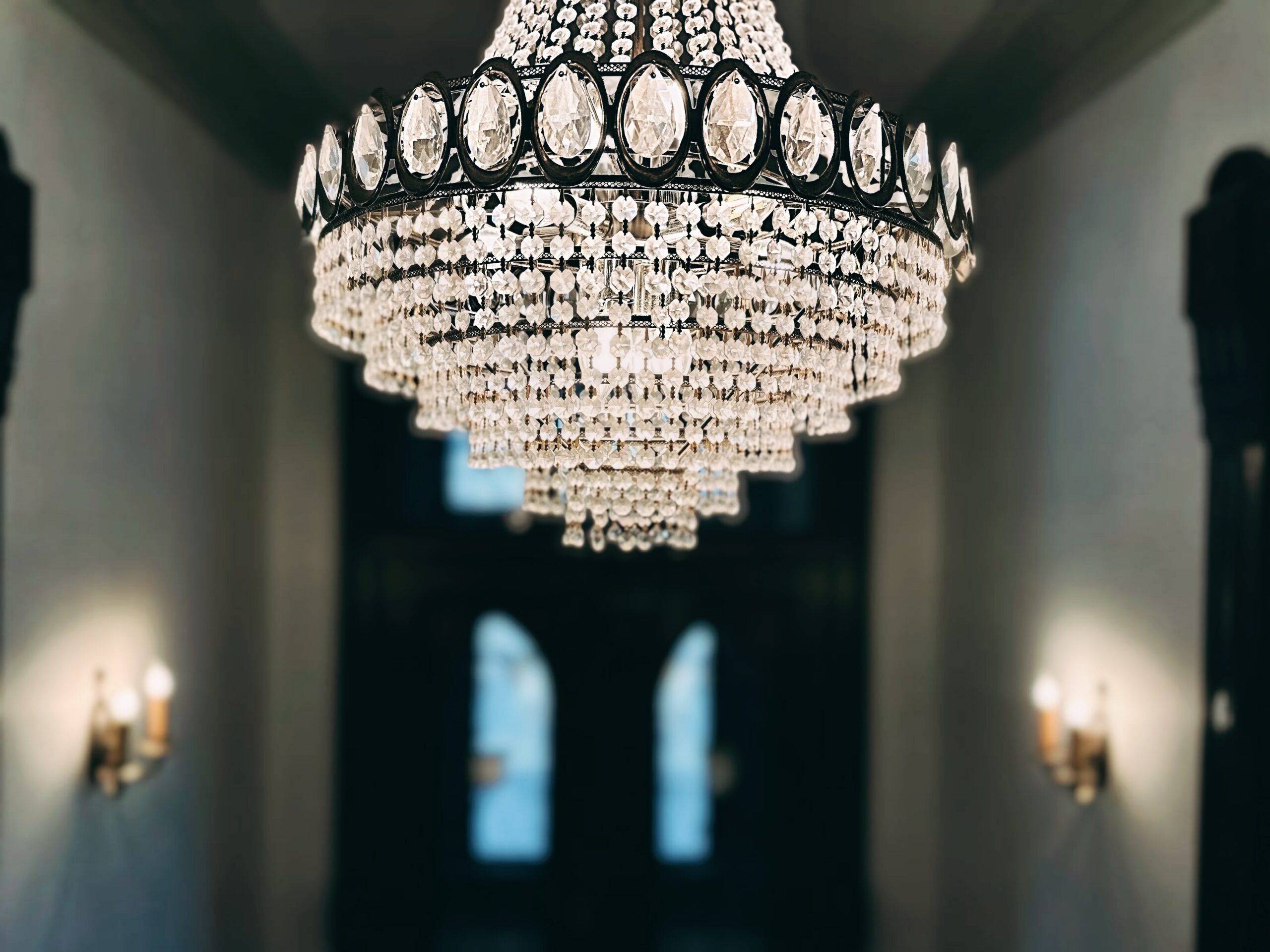 Crystal tiered chandelier in the central hallway of Parker and Parker Attorneys at Law with brass wall sconces